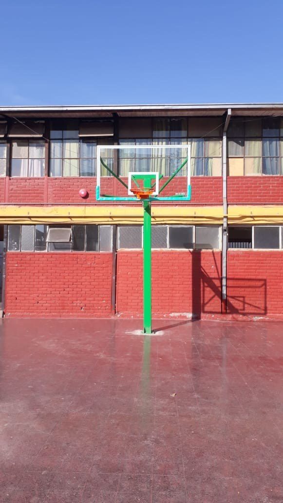 Aro de básquetbol con tablero instalado y anclado en la cancha de un colegio