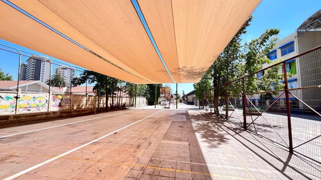 Circulación exterior de un colegio cubierta con velas de sombra a lo largo del recorrido