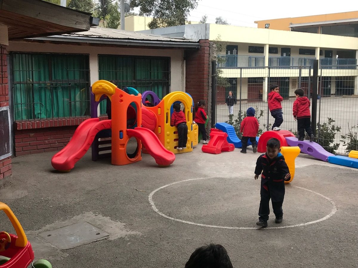 Juego de plaza infantil instalado sobre piso de goma en el patio de una escuela