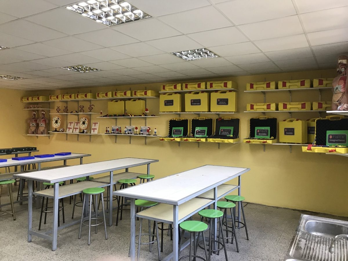 Laboratorio de ciencias escolar equipado con mesones, piso antideslizante y maletas didácticas en estantería